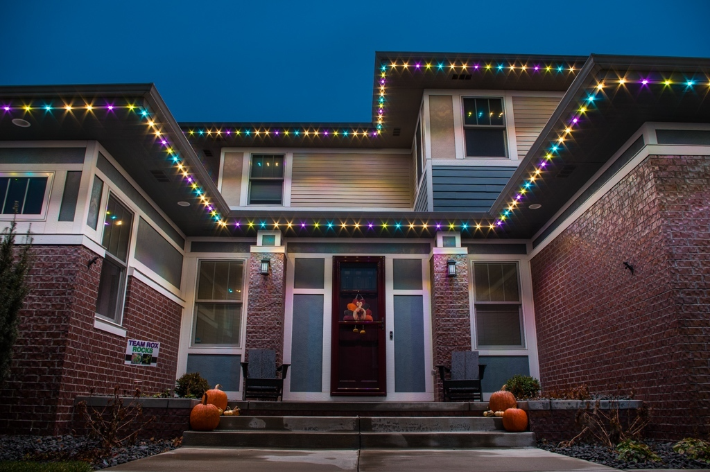 A cozy house is adorned with colorful lights and pumpkins, creating a festive atmosphere
