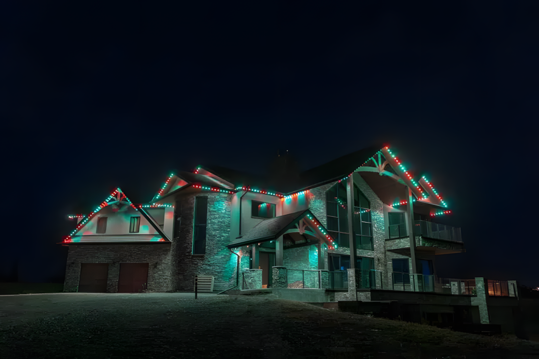 A uniquely designed house is illuminated with colorful lights against a night sky